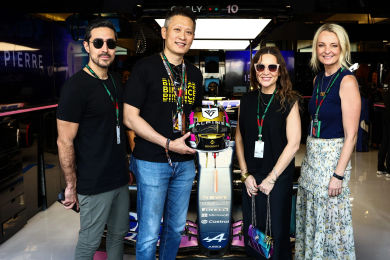 Paddock Club guests posing with an Alpine car and helmet