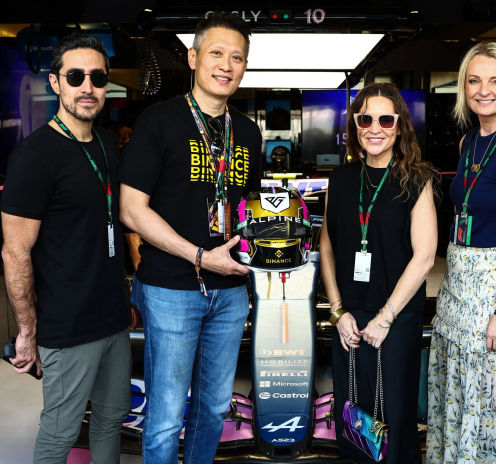 Paddock Club guests posing with an Alpine car and helmet