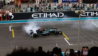 A Mercedes F1 car doing tricks on the Main Straight of Yas Marina Circuit