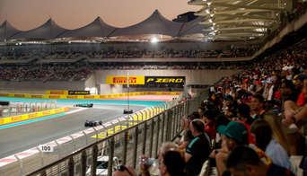 F1 cars racing on the Yas Marina Circuit past the grandstands filled with fans