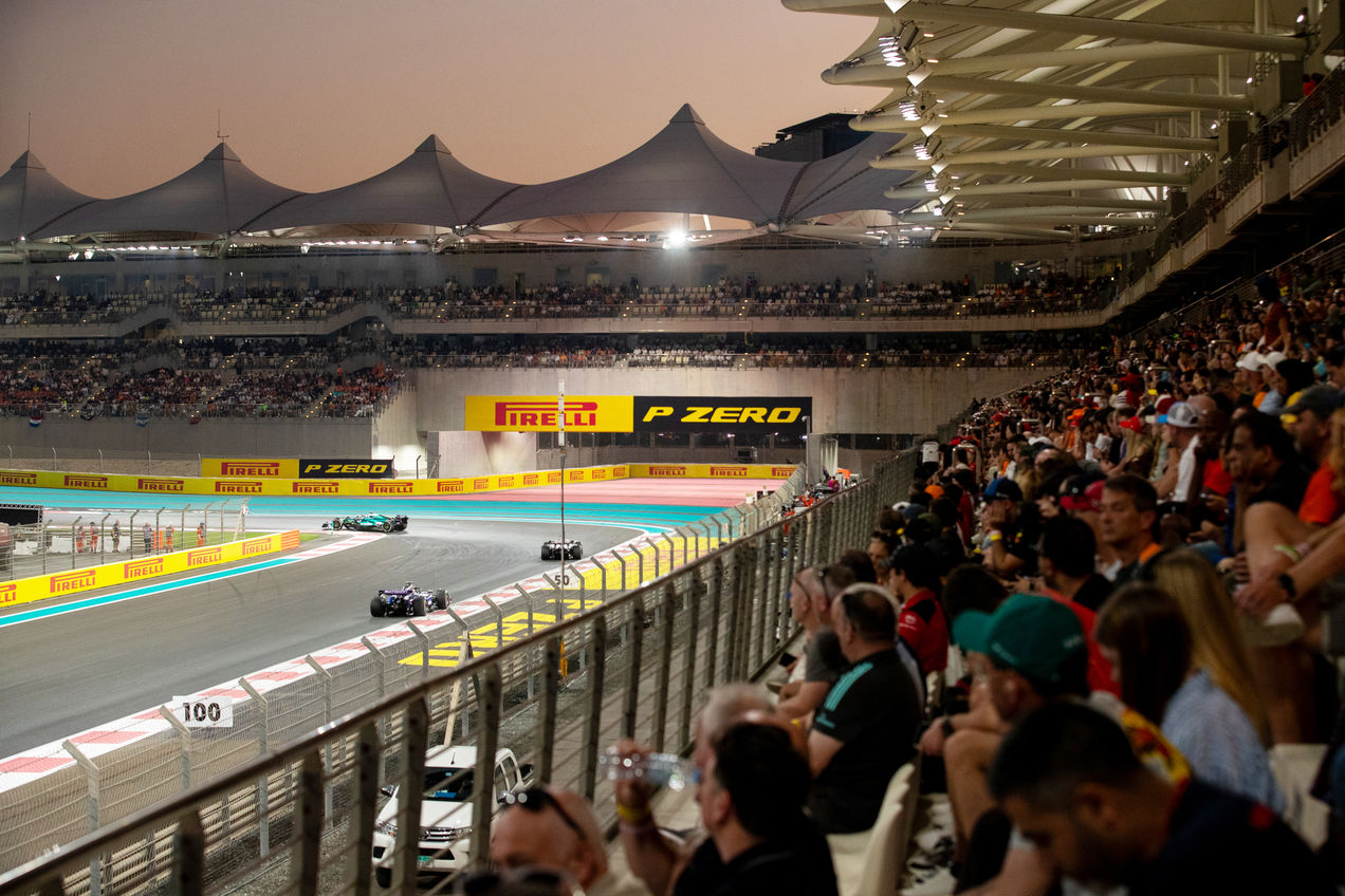 F1 cars racing on the Yas Marina Circuit past the grandstands filled with fans