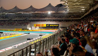 F1 cars racing on the Yas Marina Circuit past the grandstands filled with fans
