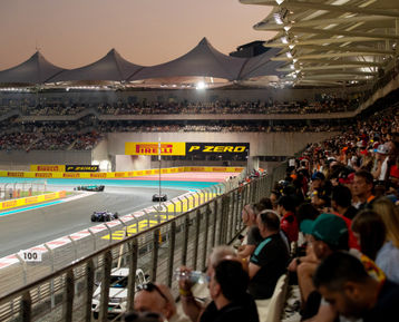 F1 cars racing on the Yas Marina Circuit past the grandstands filled with fans