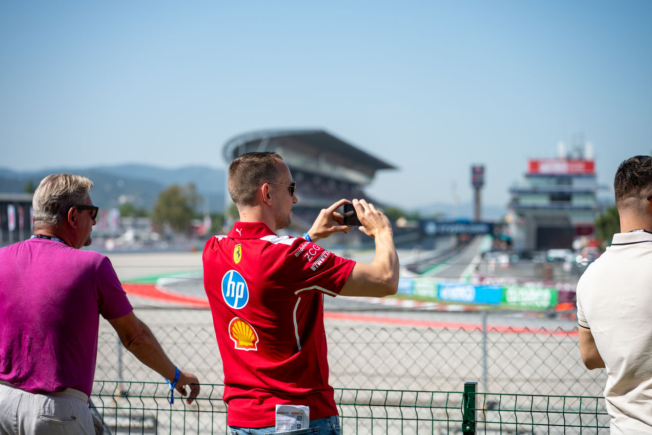 Un aficionado a Ferrari en el Garden Club tomando una foto de los coches de F1.