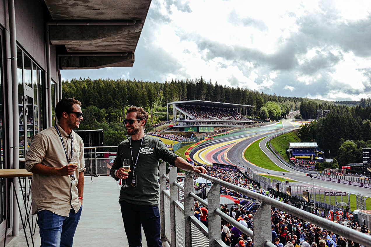 Gasten genieten van een glas champagne op het balkon van de Gold 2 VIP Lounge