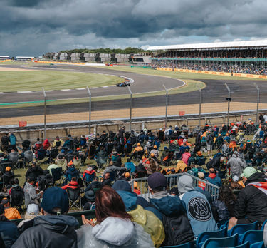 Une voiture de F1 dans le virage de Chapel alors que les fans regardent depuis la tribune.