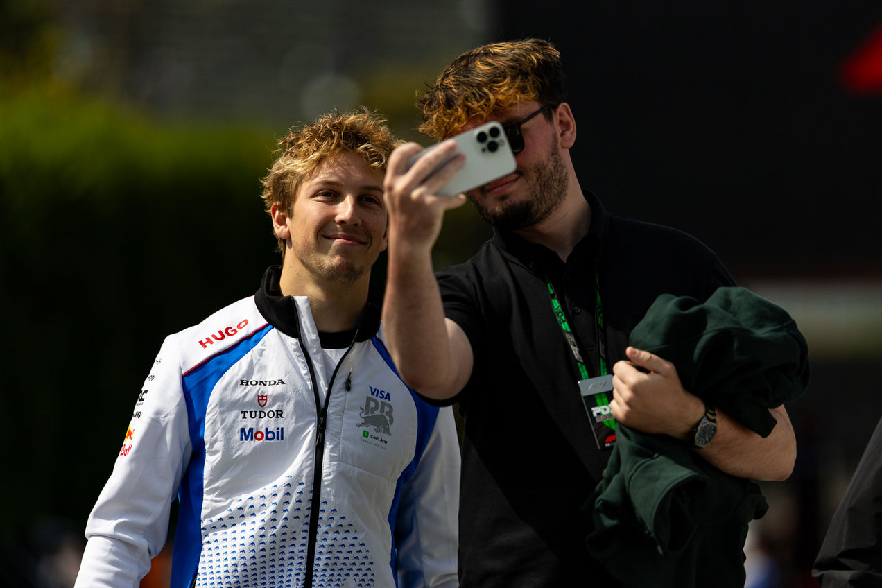 Liam Lawson posing for a selfie with a fan in the paddock area