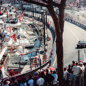 Espectadores en un yate ven un Alpine F1 corriendo por el puerto de Mónaco