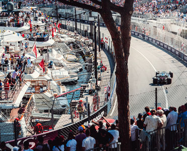 Spectators on a yacht see an Alpine F1 car racing through the harbor of Monaco