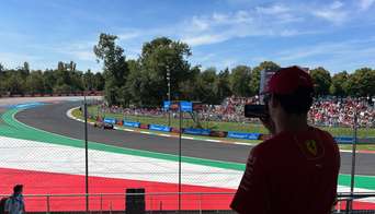 A Ferrari fan filming an F1 car driving past Grandstand 22 on Monza Circuit