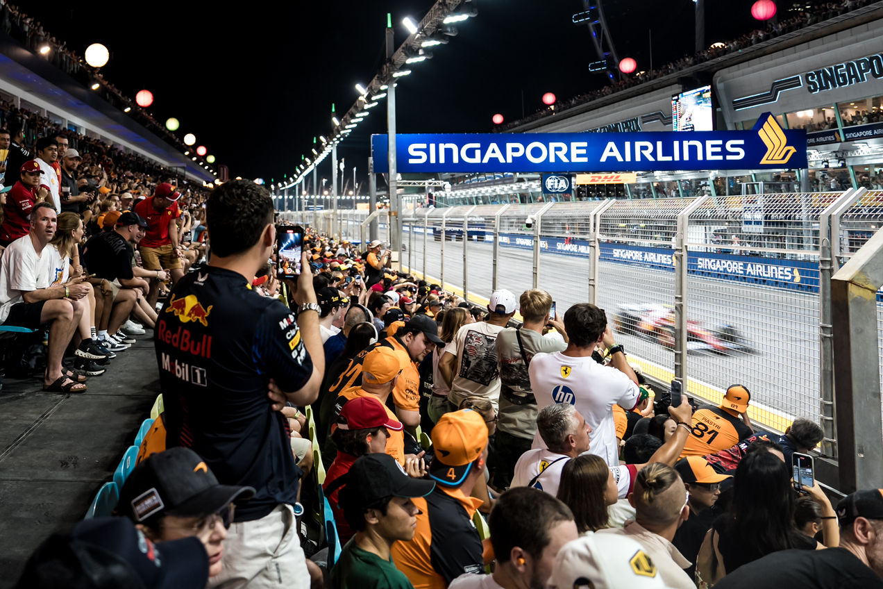 Ferrari car tearing down main straight with fans on the Pit Grandstand watching
