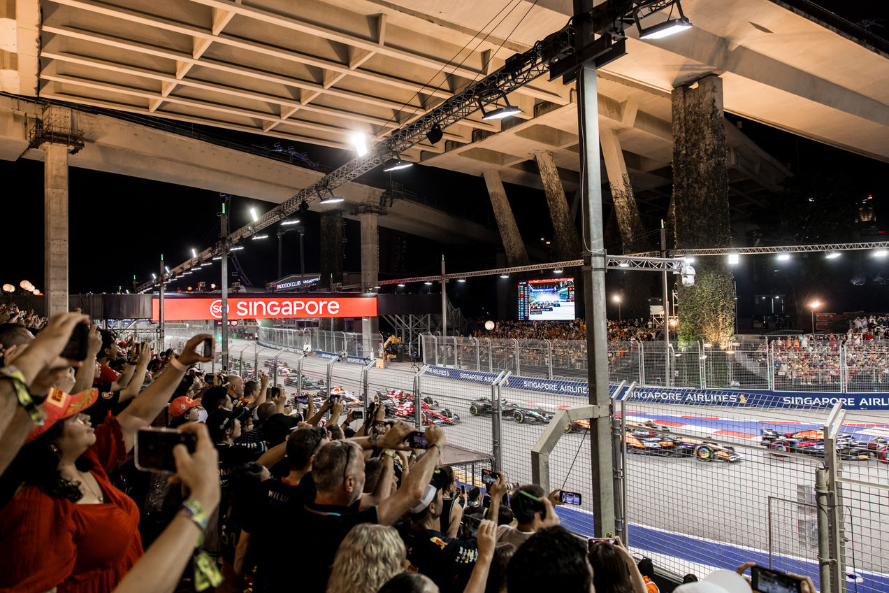 F1 cars taking on the first turn at the Singapore GP in front of F1 fans