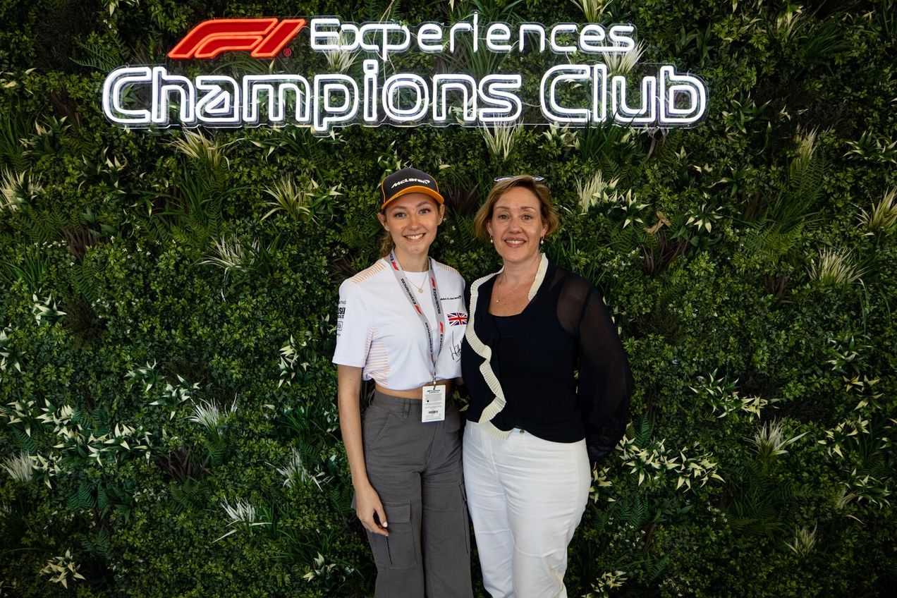 Deux invités de F1 Experiences posent devant l'enseigne du Club des Champions lors du GP du Qatar.