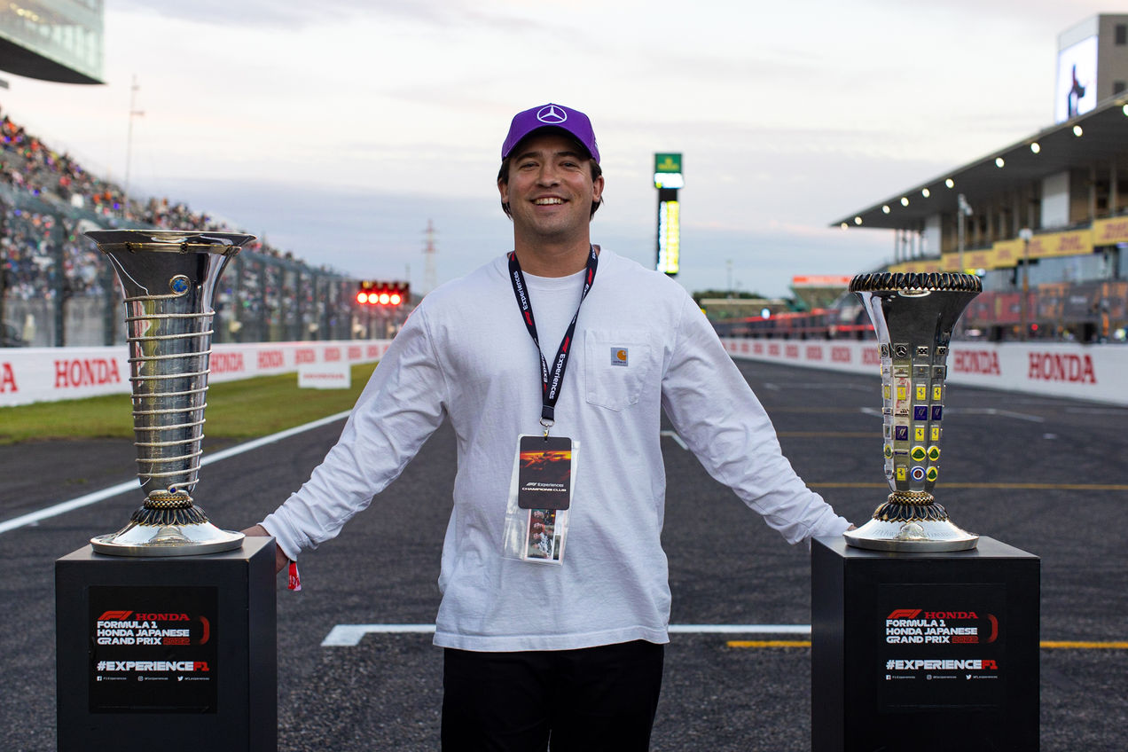 An F1 fan poses for a photo with the championship trophies