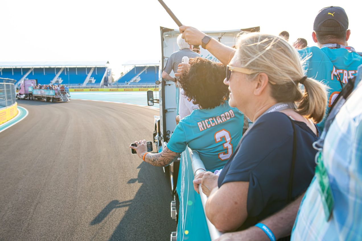 F1 supporters riding in a flatbed track around the Miami GP circuit