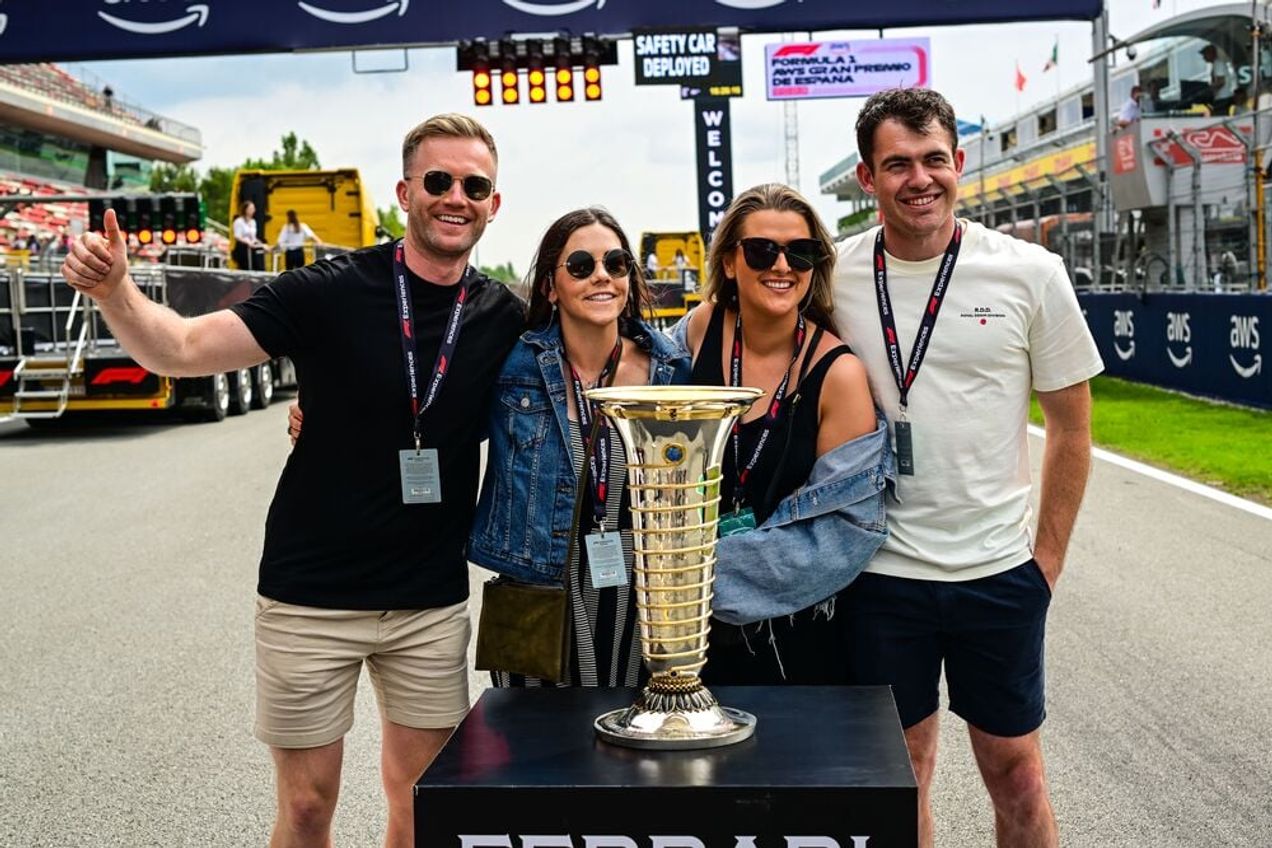 Eine Gruppe von F1-Fans posiert für ein Foto mit der Meisterschaftstrophäe beim spanischen GP