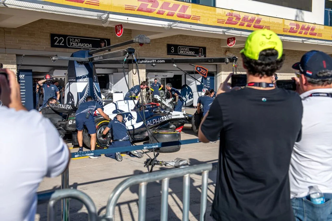 Een F1 maakt een foto van het AlphaTauri-team dat aan de F1-auto werkt