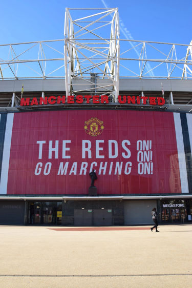 Old Trafford stadion met “The Reds Go Marching On” banner van Manchester United