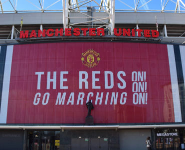 Estadio Old Trafford con el banner « The Reds Go Marching On » del Manchester United