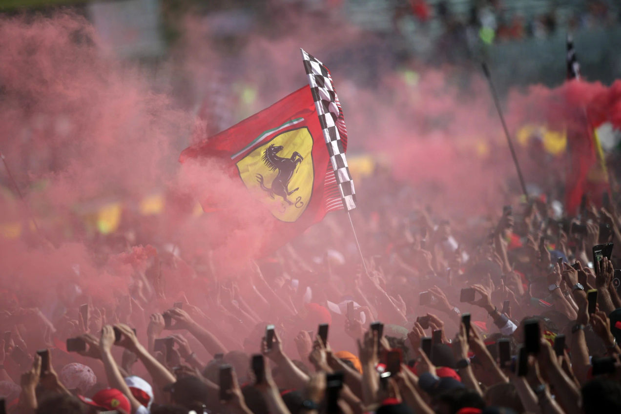A crowd covered in red smoke raise a Ferrari flag at the Monza GP