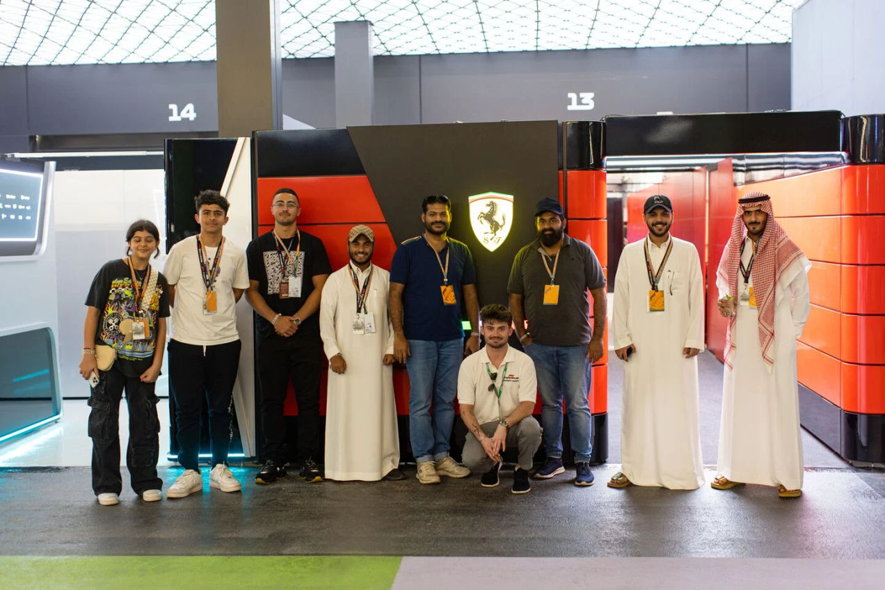 Un groupe d'invités de F1 Experiences pose pour une photo dans le paddock Ferrari